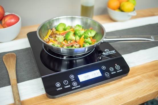 Portable induction cooktop with pan of vegetables